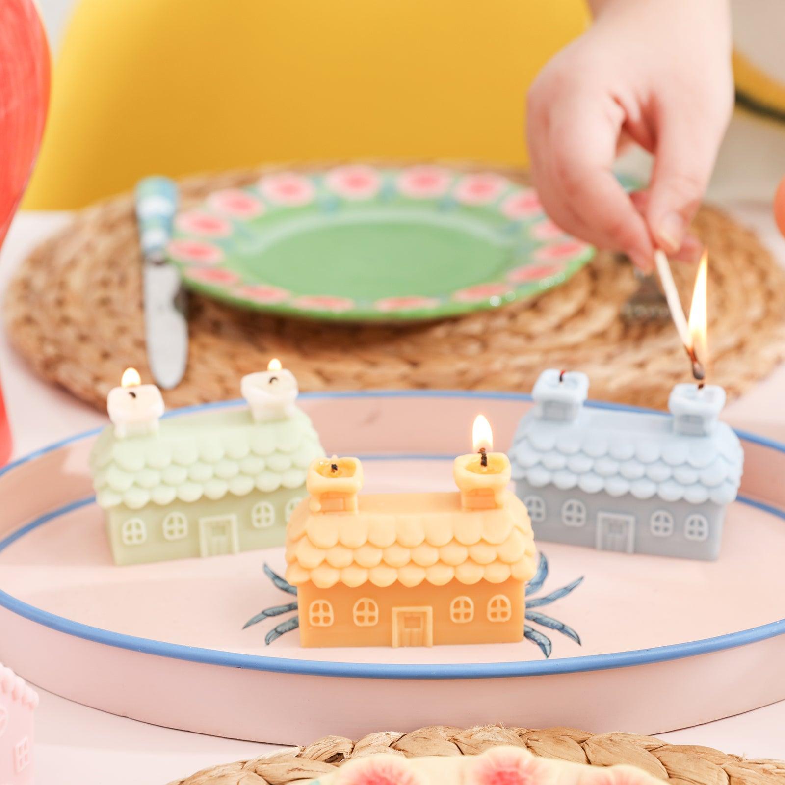 Three lighted double chimney house candles are arranged in a tray.