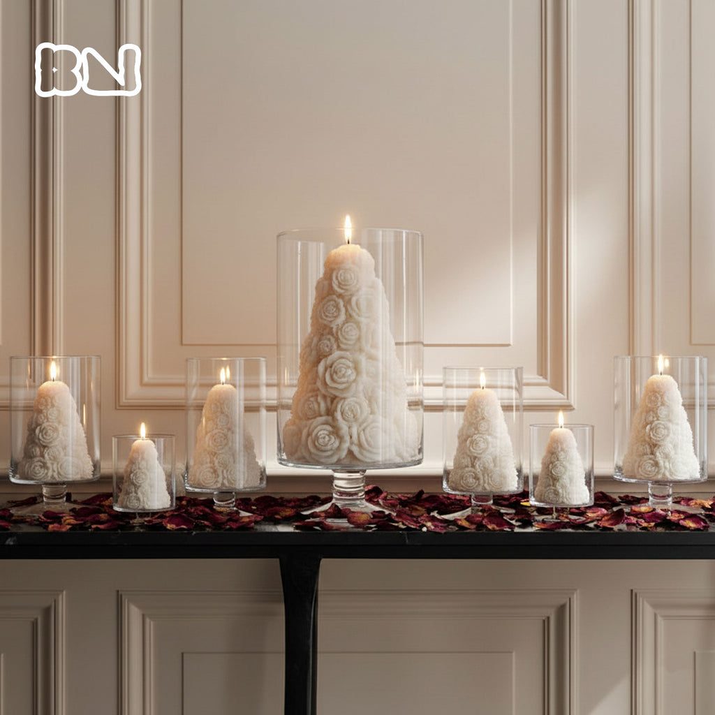 Ivory rose tree pillar candles burning inside glass hurricane vases on a mantel, styled as romantic wedding or holiday table centerpieces - Boowan Nicole