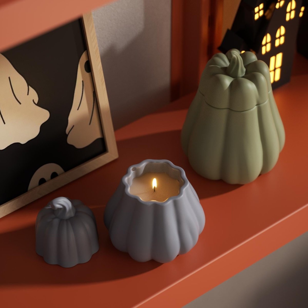 Blue and green pumpkin-shaped candle jars on an orange shelf, styled for Halloween home decor - Boowan Nicole