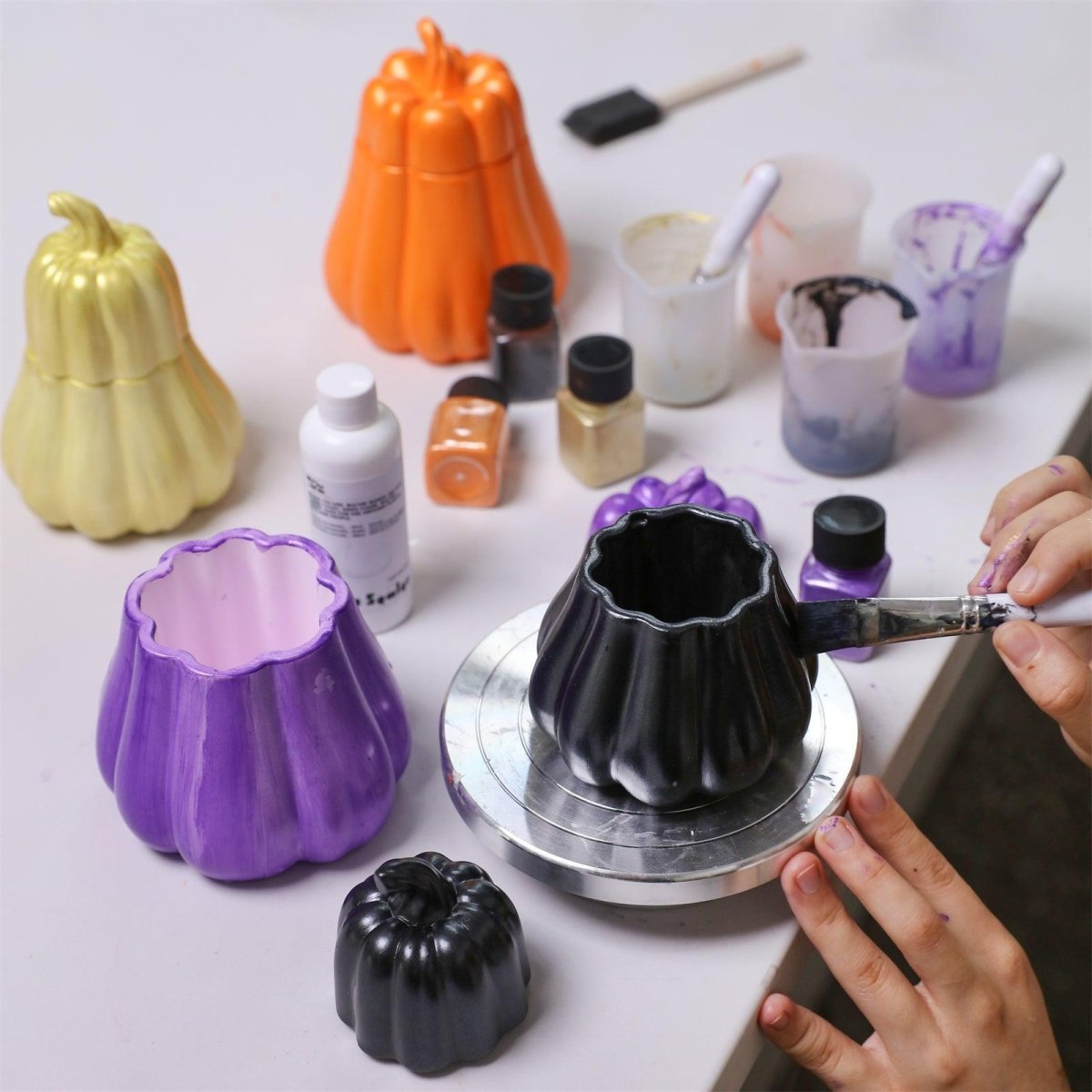 Hand painting a pumpkin-shaped candle jar with glossy black varnish and mica powder for Halloween DIY crafts - Boowan Nicole