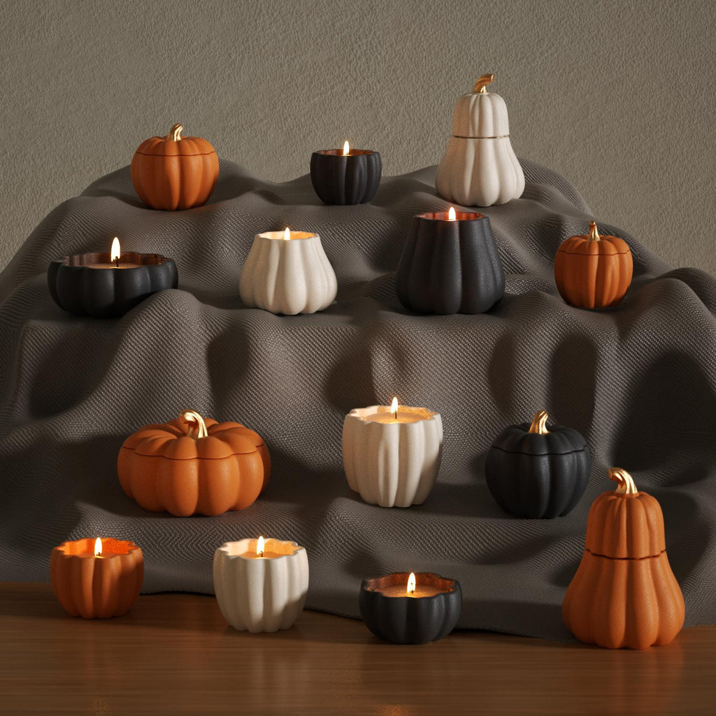 Fall-themed pumpkin candle collection in black, orange, and cream on fabric display - Boowan Nicole