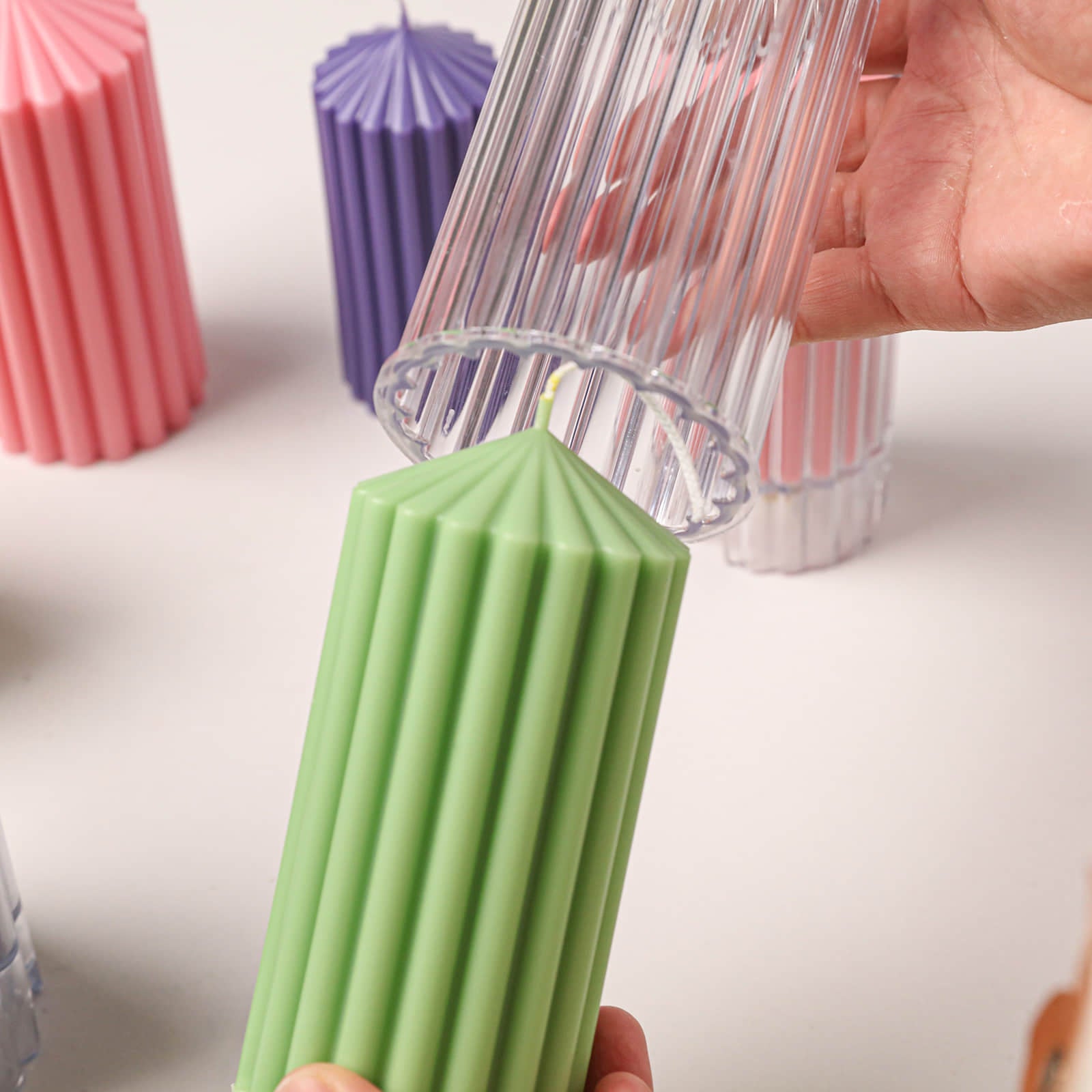 Demolding a finished green ribbed pillar candle from a clear acrylic mold - Boowan Nicole