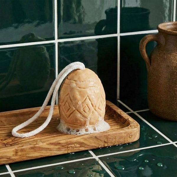 Foamy geometric egg soap on a wooden tray in a dark-tiled bathroom -Boowan Nicole