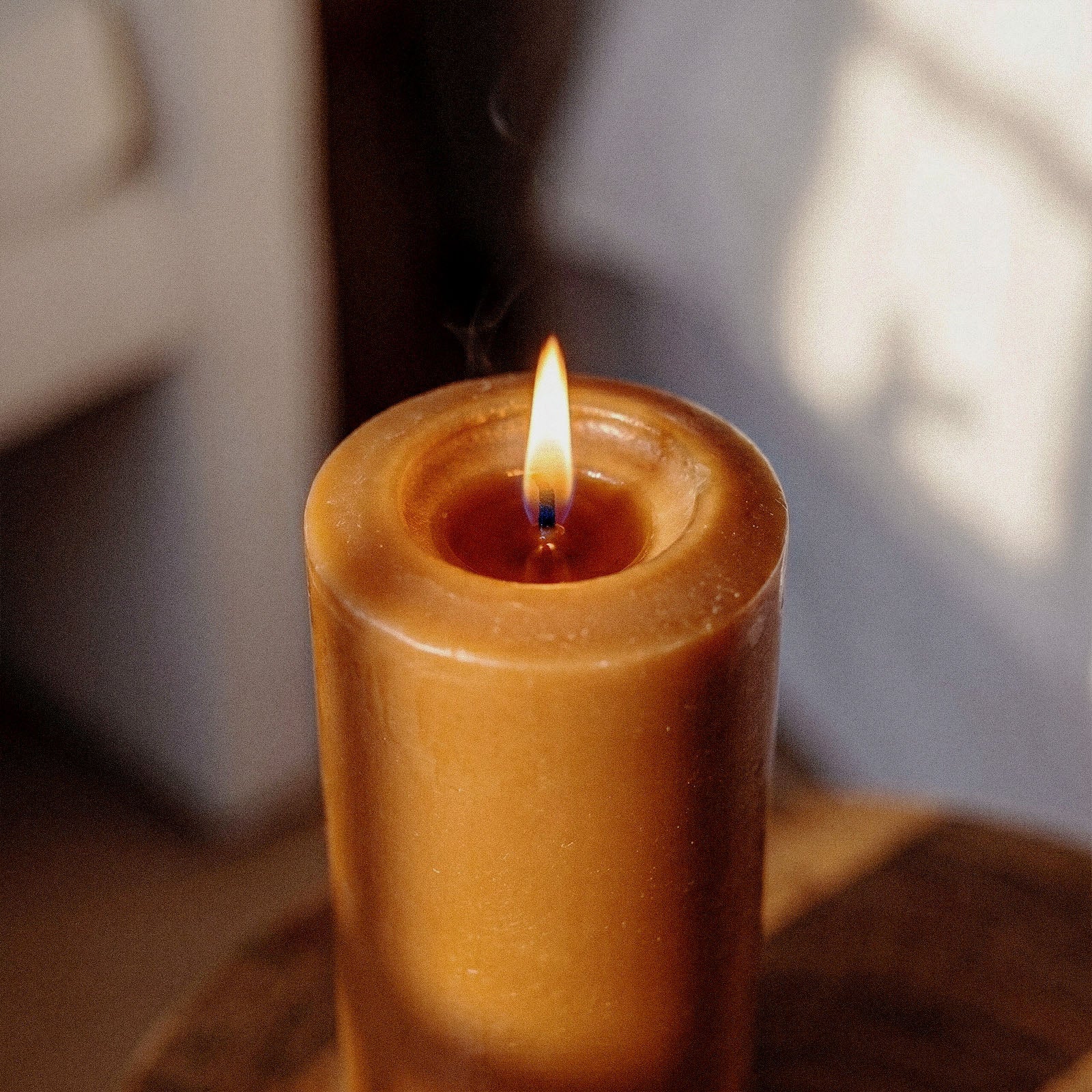 Classic Pointed Pillar Acrylic Candle Mold Collection, close-up of a lit brown pillar candle with melted wax pool - Boowan Nicole