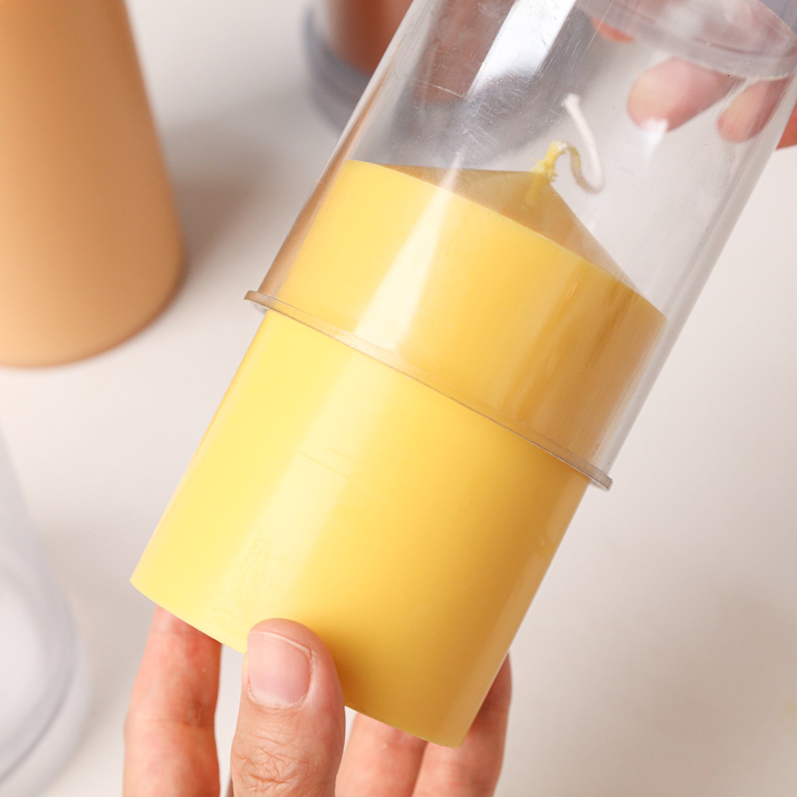 Classic Pointed Pillar Acrylic Candle Mold Collection, unmolding a finished yellow pillar candle from the clear acrylic mold - Boowan Nicole