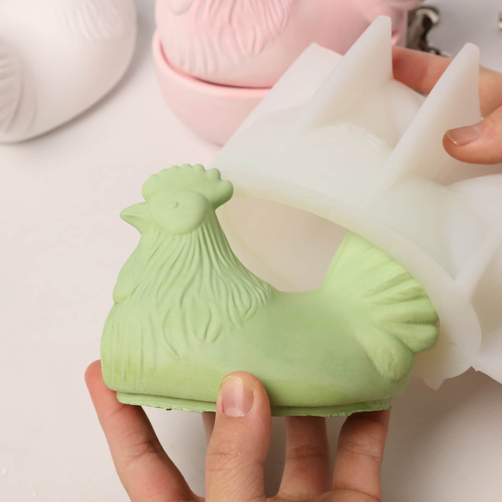 Releasing a light green hen jar lid from a flexible white silicone mold, demonstrating easy demolding and high-detail feather texture - Boowan Nicole