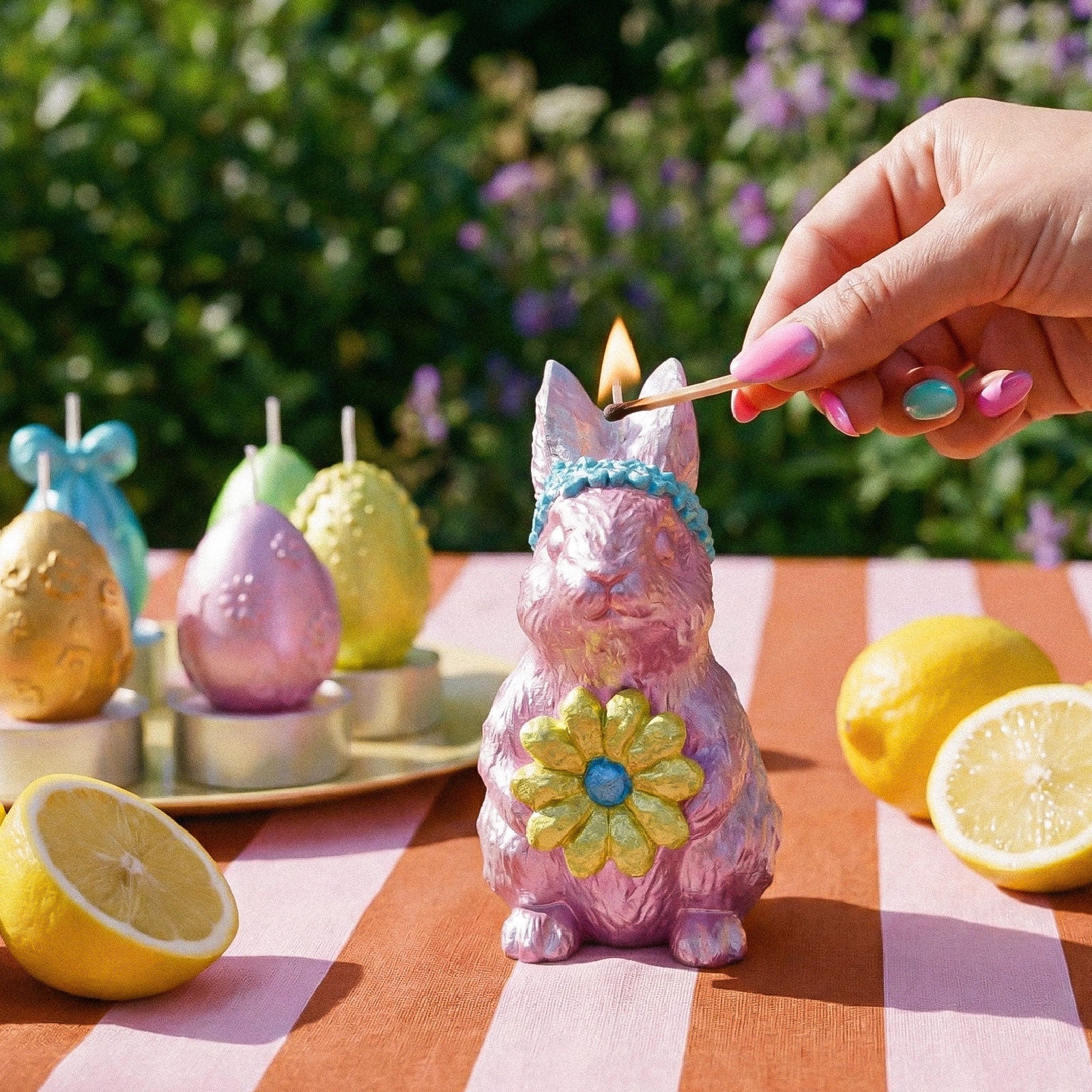 Lighting a pink bunny-shaped Easter candle with a match in an outdoor setting -Boowan Nicole
