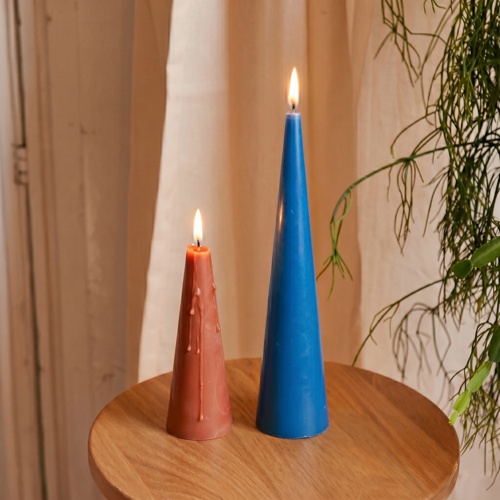 Lit Red & Blue Cone Candles on Wooden Table - Boowan Nicole