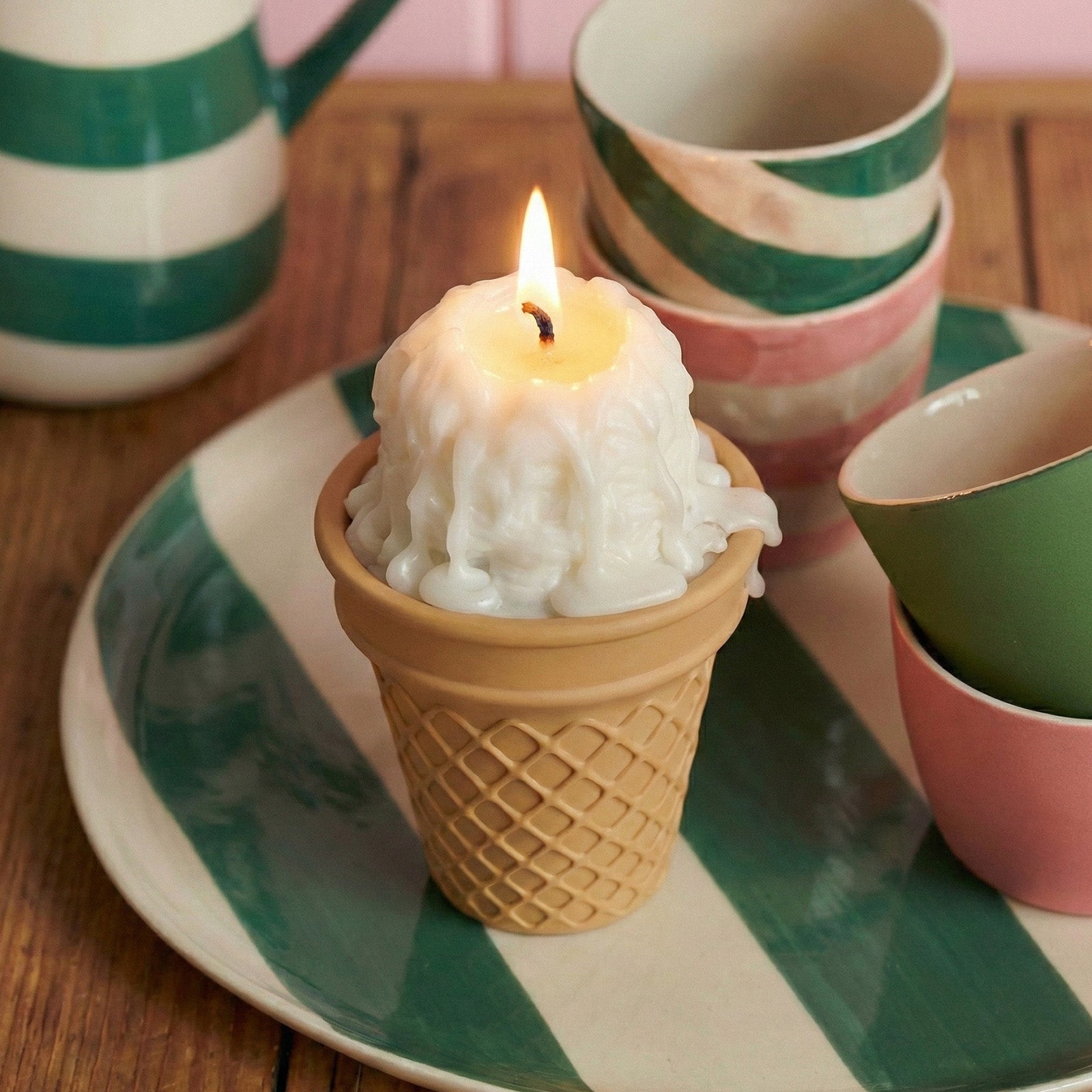 Lit vanilla ice cream scoop candle in a tan waffle cone holder, styled on a green and white striped plate with matching tableware - Boowan Nicole