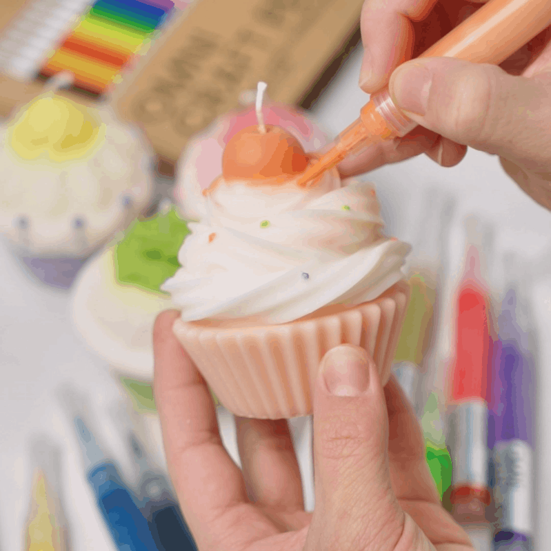 Using a colorful paintbrush to hand-paint and add detailed decorations to a finished dessert candle - Boowan Nicole