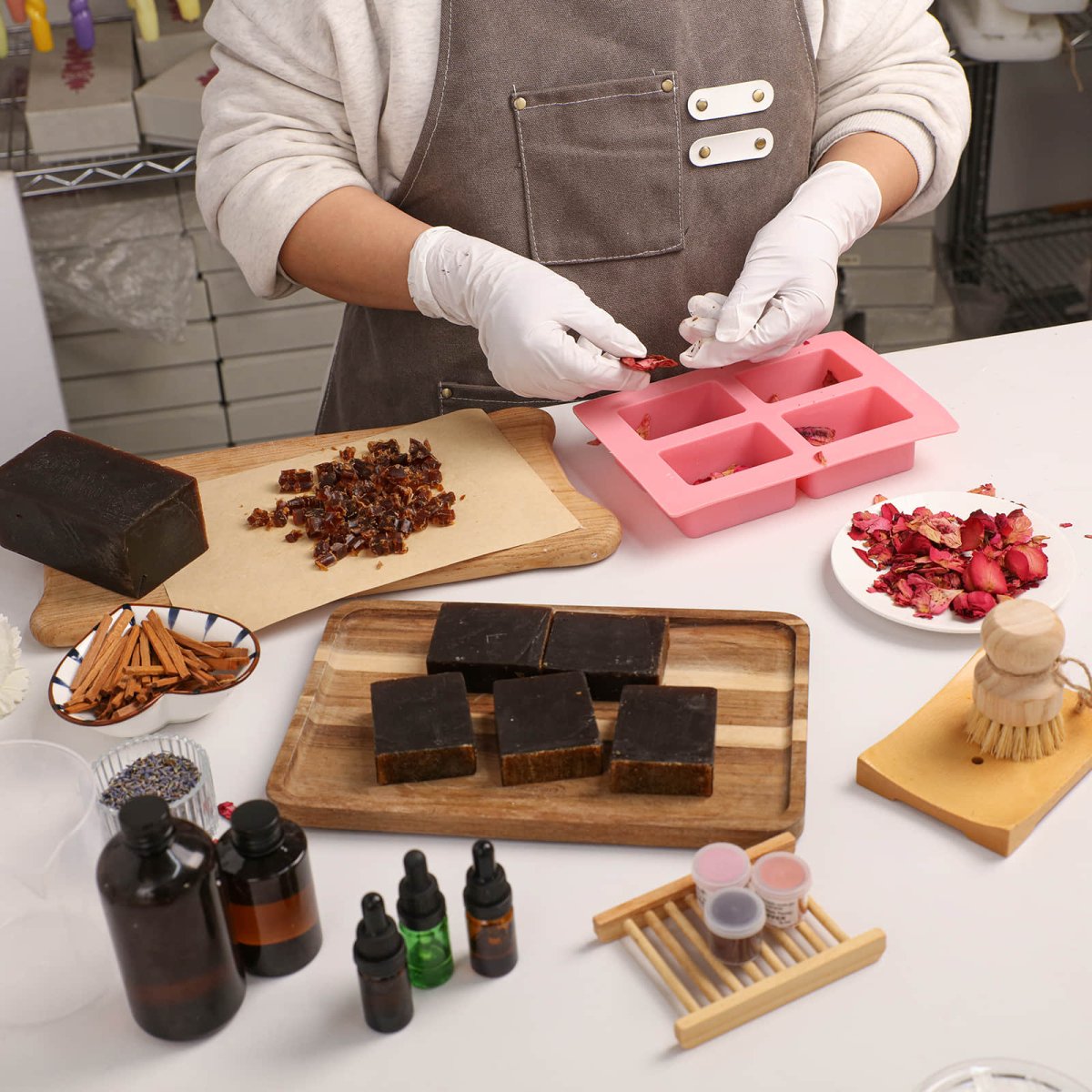 Handcrafting Damask Rose Essential Oil Soap Bars using natural dried rose petals, essential oils, and botanical ingredients on a white workspace - Boowan Nicole