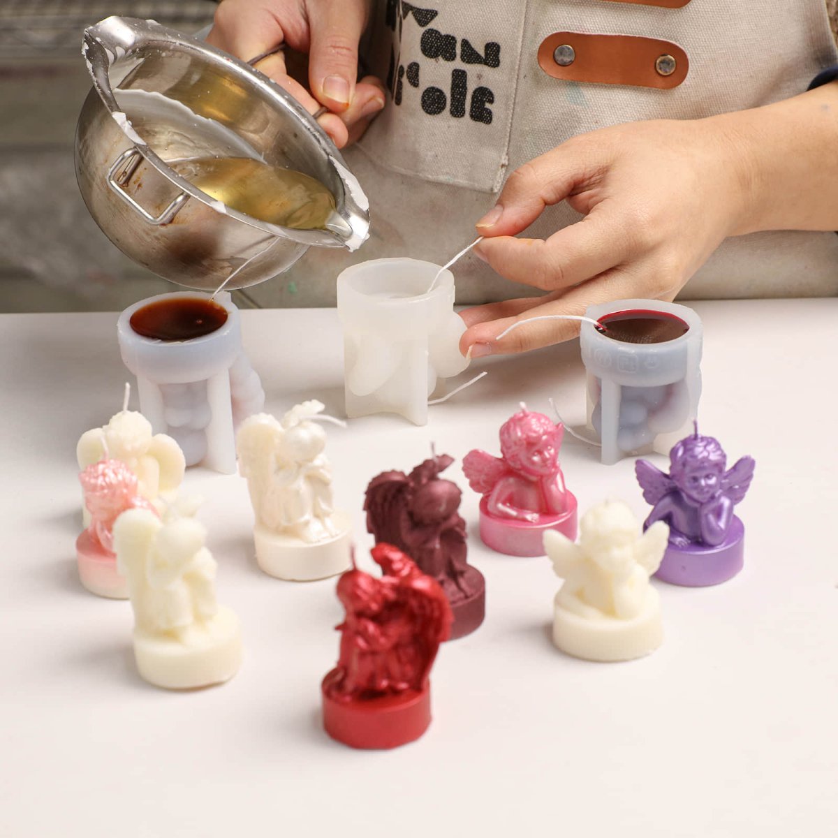 Hand-pouring wax into silicone molds to create cherub angel tea light candles in various colors - Boowan Nicole