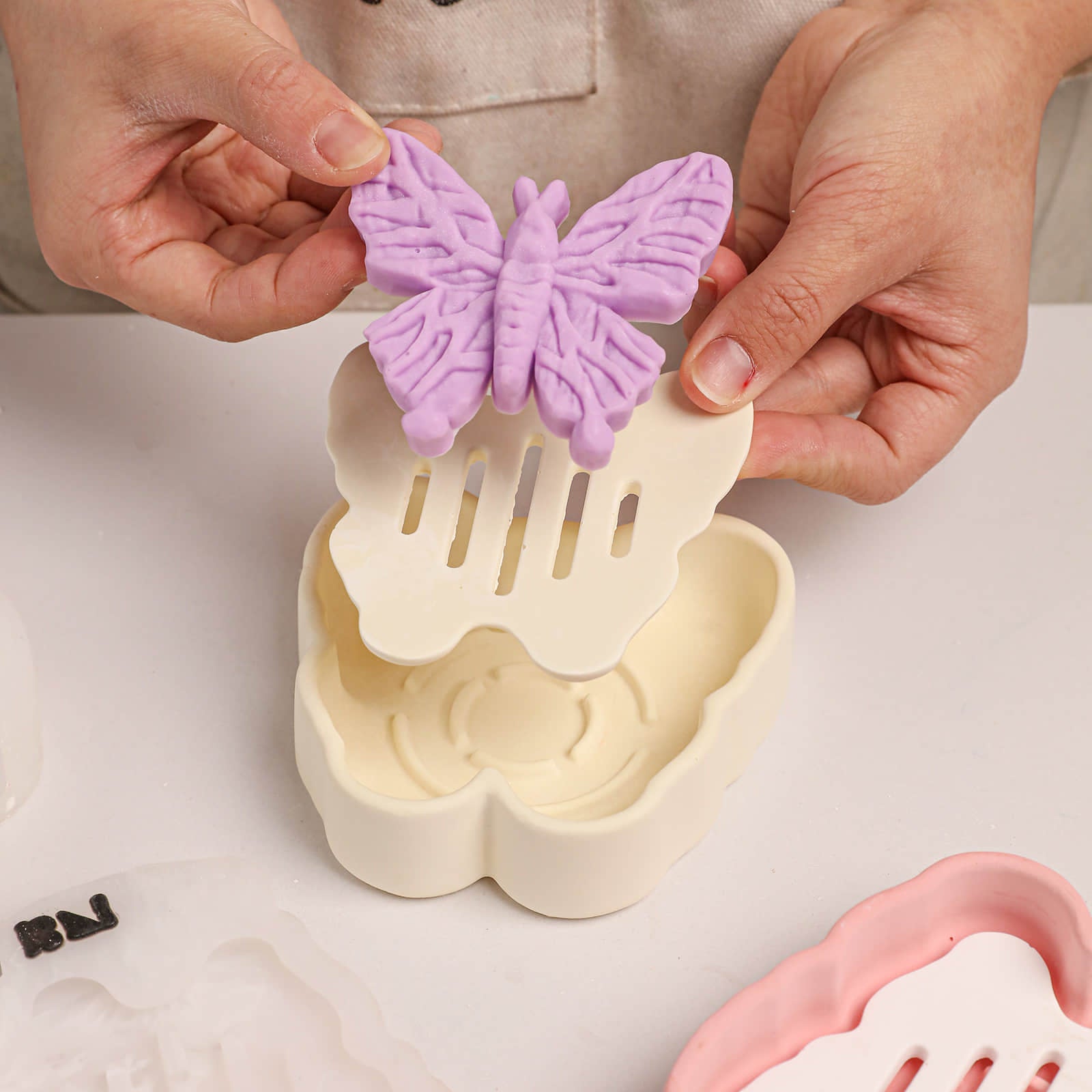 Placing a purple butterfly soap onto a butterfly-shaped drainage dish - Boowan Nicole	