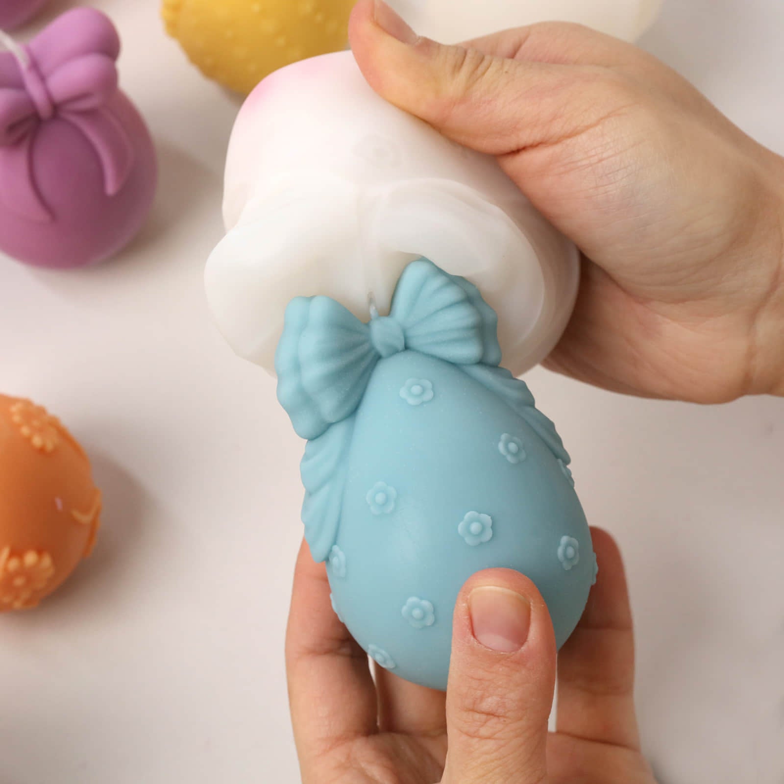 Demolding a blue bow-adorned Easter egg candle from a silicone mold - Boowan Nicole