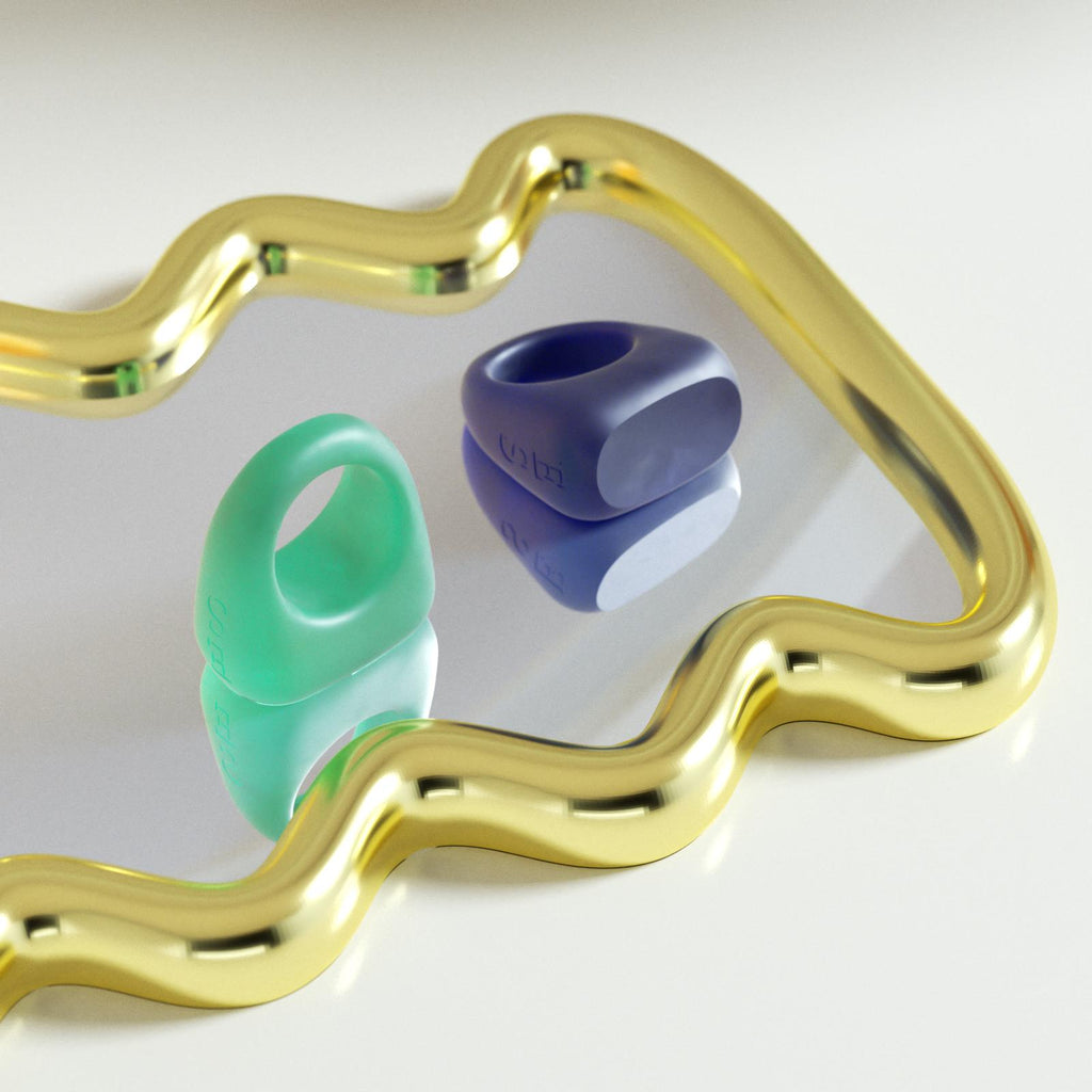 Blue and green resin rings placed on a wavy textured mirror, creating a stylish and modern reflection-Boowan Nicole