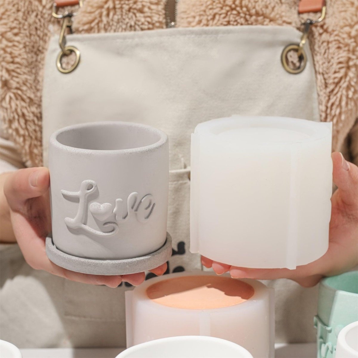 Showcasing a cement-colored flowerpot with an embossed 'Love' design-Boowan Nicole