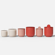 Set of geometric candle jars in beige, pink, and red, with flat and knob lids, displayed in size order - Boowan Nicole
