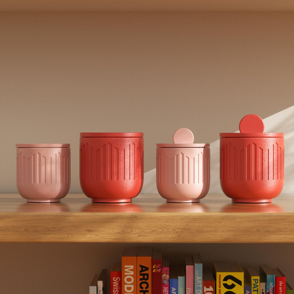 Pink and red geometric candle jars with lids displayed on wooden shelf - Boowan Nicole