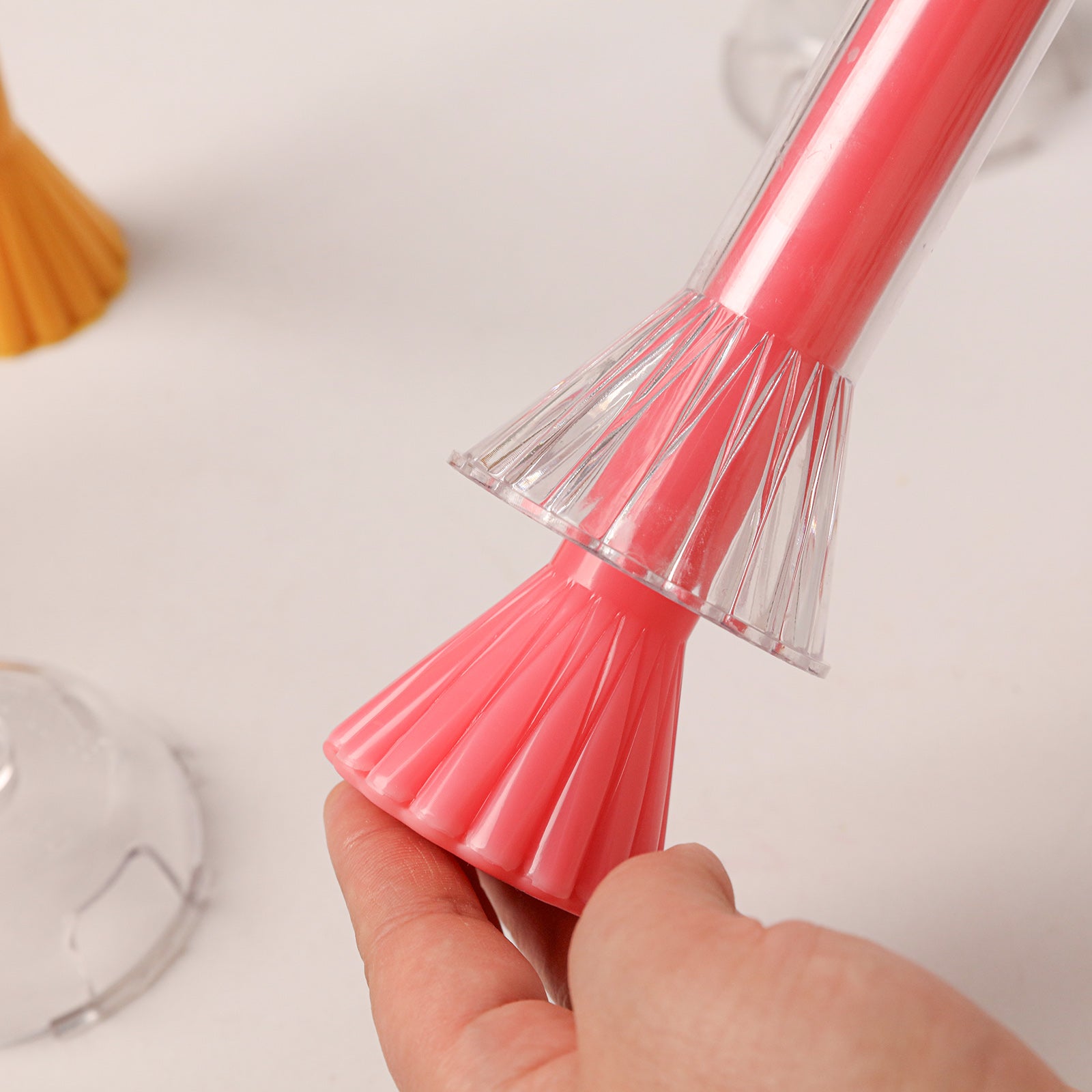 Demolding a pink taper candle from a clear fan-shaped mold, highlighting the detailed fluted base texture. -Boowan Nicole