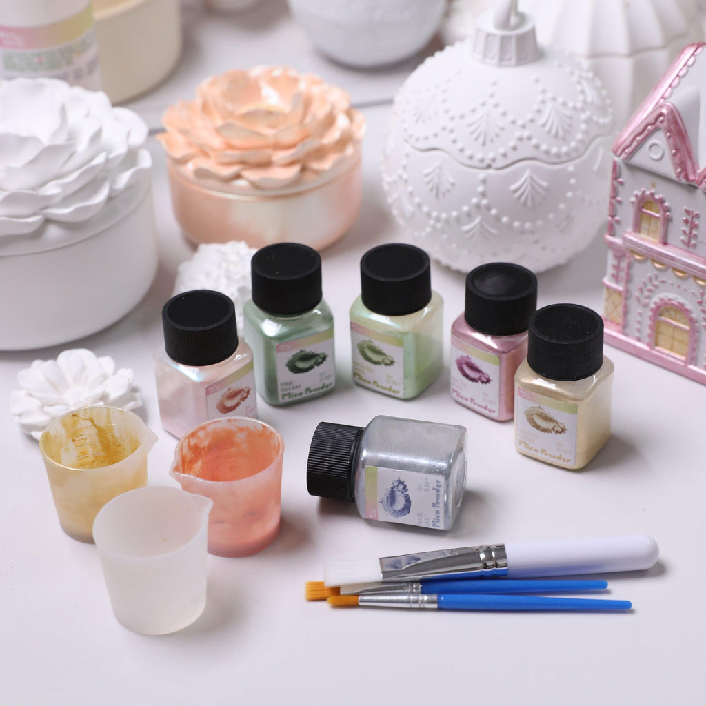 Set of mica powder jars, mixing cups, and paintbrushes for DIY candle decorating, displayed with floral and house-shaped candle jars - Boowan Nicole