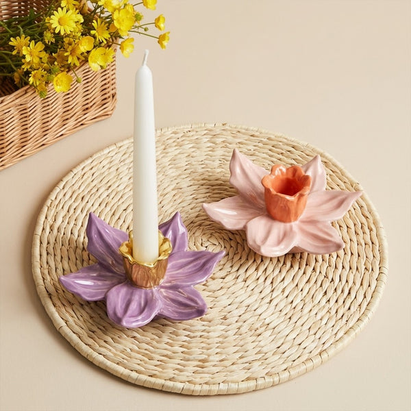 Purple and pink daffodil candle holders with taper candles on a woven mat - Boowan Nicole