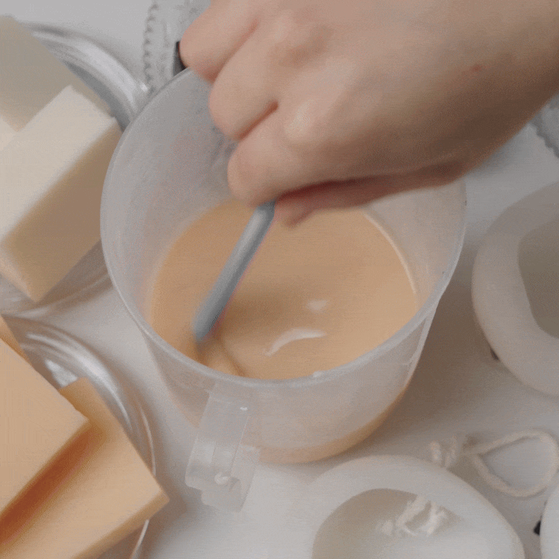 Stirring melted soap base in a measuring cup for handmade soap making. - Boowan Nicole