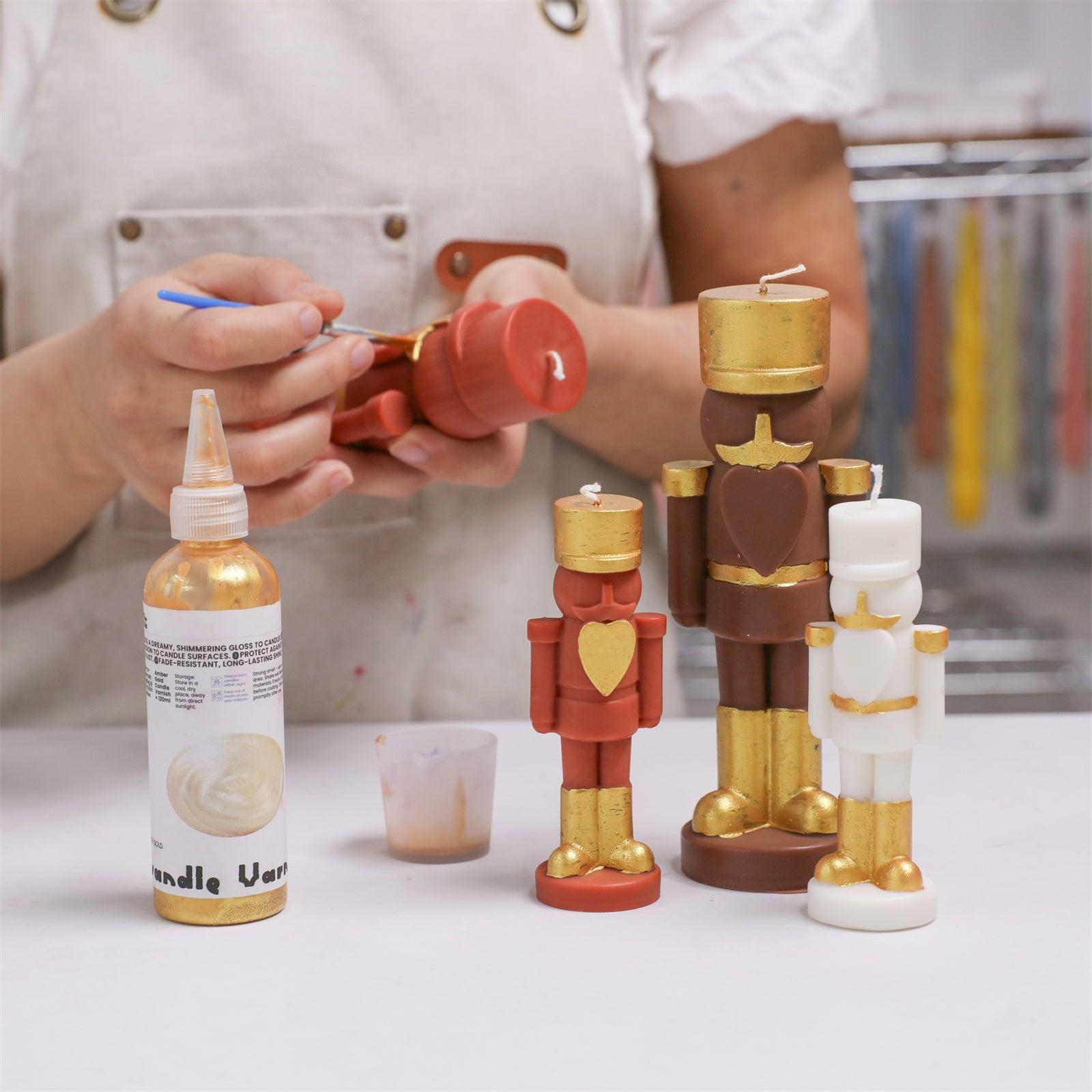 Hand-painting nutcracker candles with gold candle varnish using fine brushes—ideal for detailed festive DIY decoration -  Boowan Nicole