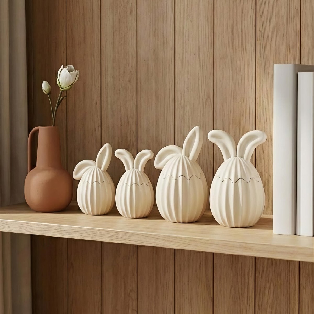 A row of four cream ribbed bunny ear jars in various sizes and ear styles displayed on a minimalist wooden shelf - Boowan Nicole