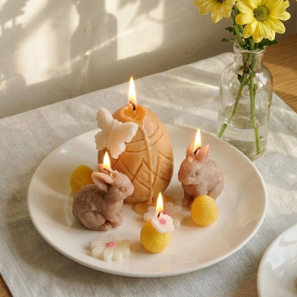 Lit Easter bunny and geometric egg candles with a white butterfly on a ceramic plate, captured in warm natural sunlight for a cozy spring ambiance - Boowan Nicole