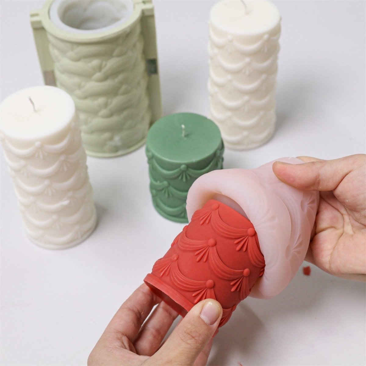 Demolding a red embossed pillar candle from a silicone mold with intricate details - Boowan Nicole