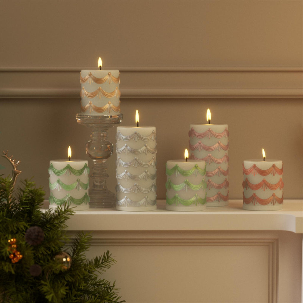 Hand-painted pillar candles with embossed garland design in soft holiday colors displayed on a mantelpiece - Boowan Nicole
