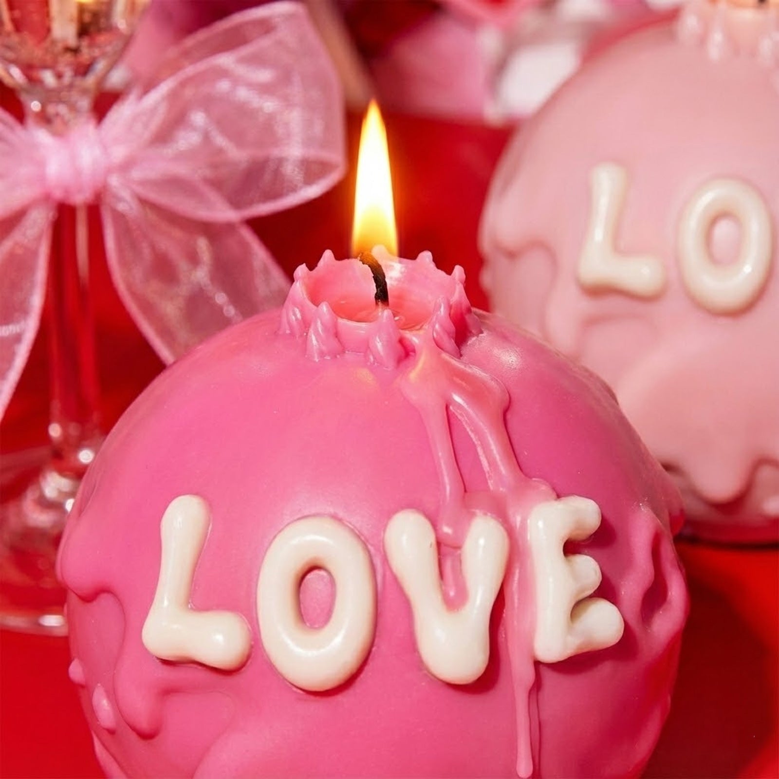 Close-up of a lit pink LOVE candle with white embossed letters and aesthetic dripping wax - Boowan Nicole