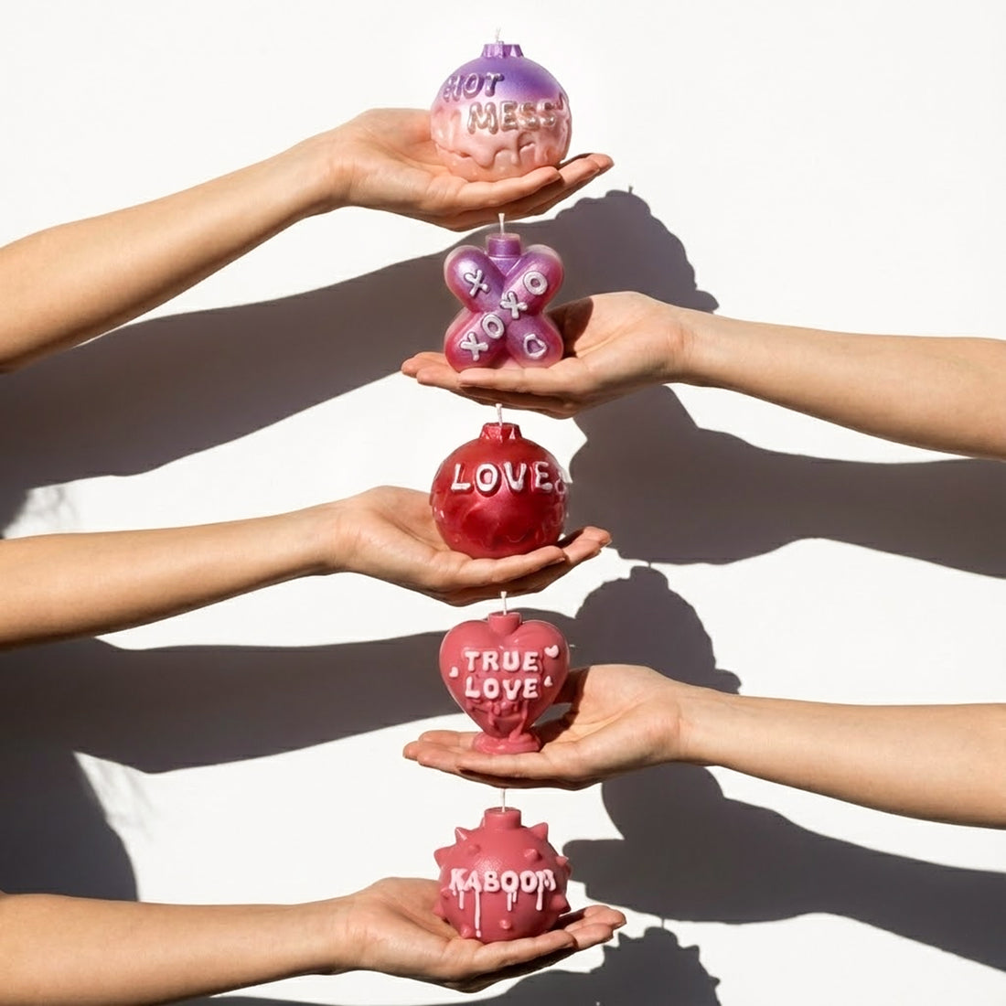Vertical hands holding Large Boomy Love 3D quote candles in Cherry Kiss & Amethyst Dream gradients - Boowan Nicole