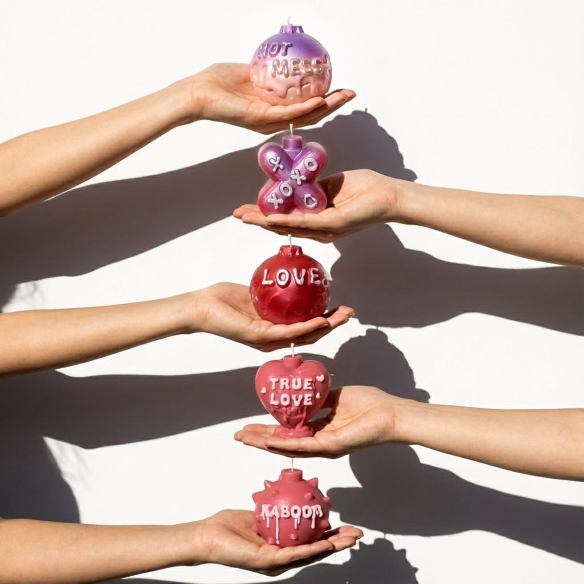 Vertical hands holding Large Boomy Love 3D quote candles in Cherry Kiss & Amethyst Dream gradients - Boowan Nicole