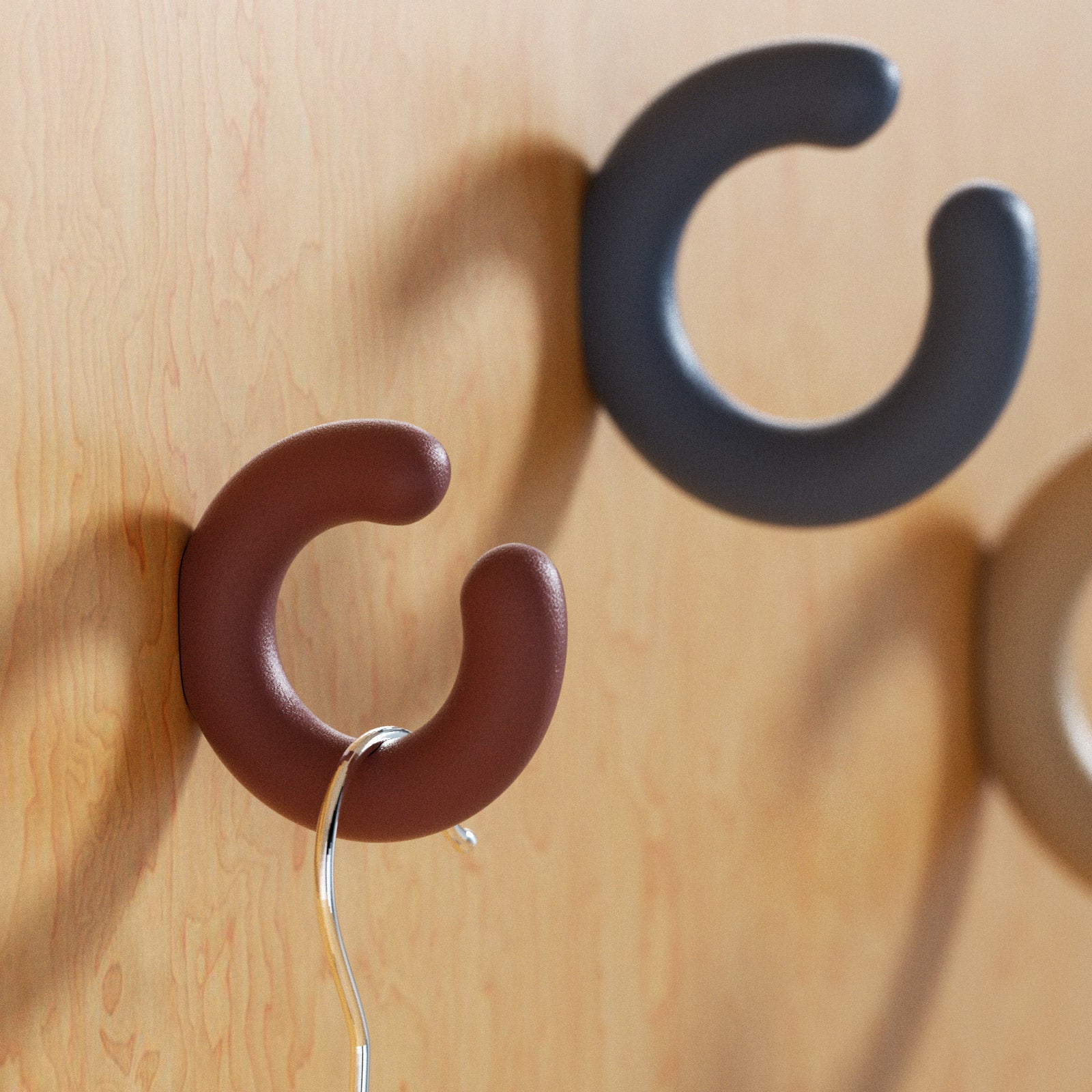 Brown C-shaped wall hook on wood wall holding a metal ring and cord - Boowan Nicole