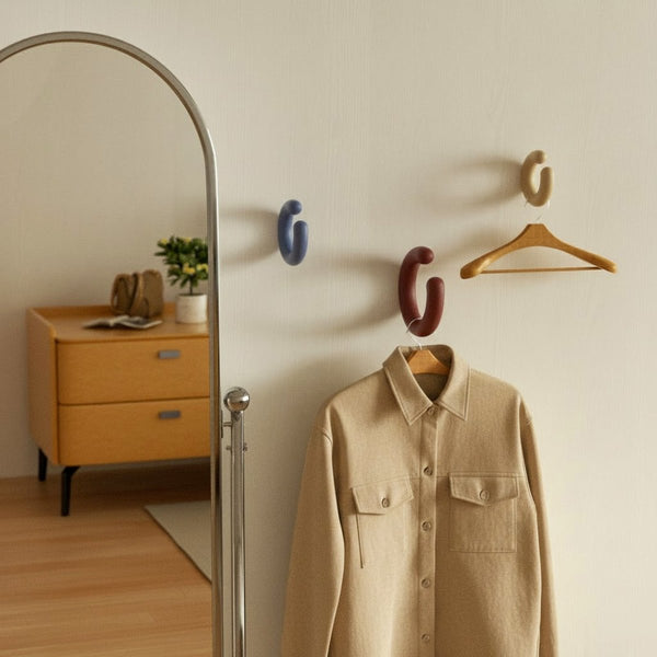 Minimal entryway wall with colorful C-shaped hooks holding a wooden hanger and beige jacket - Boowan Nicole