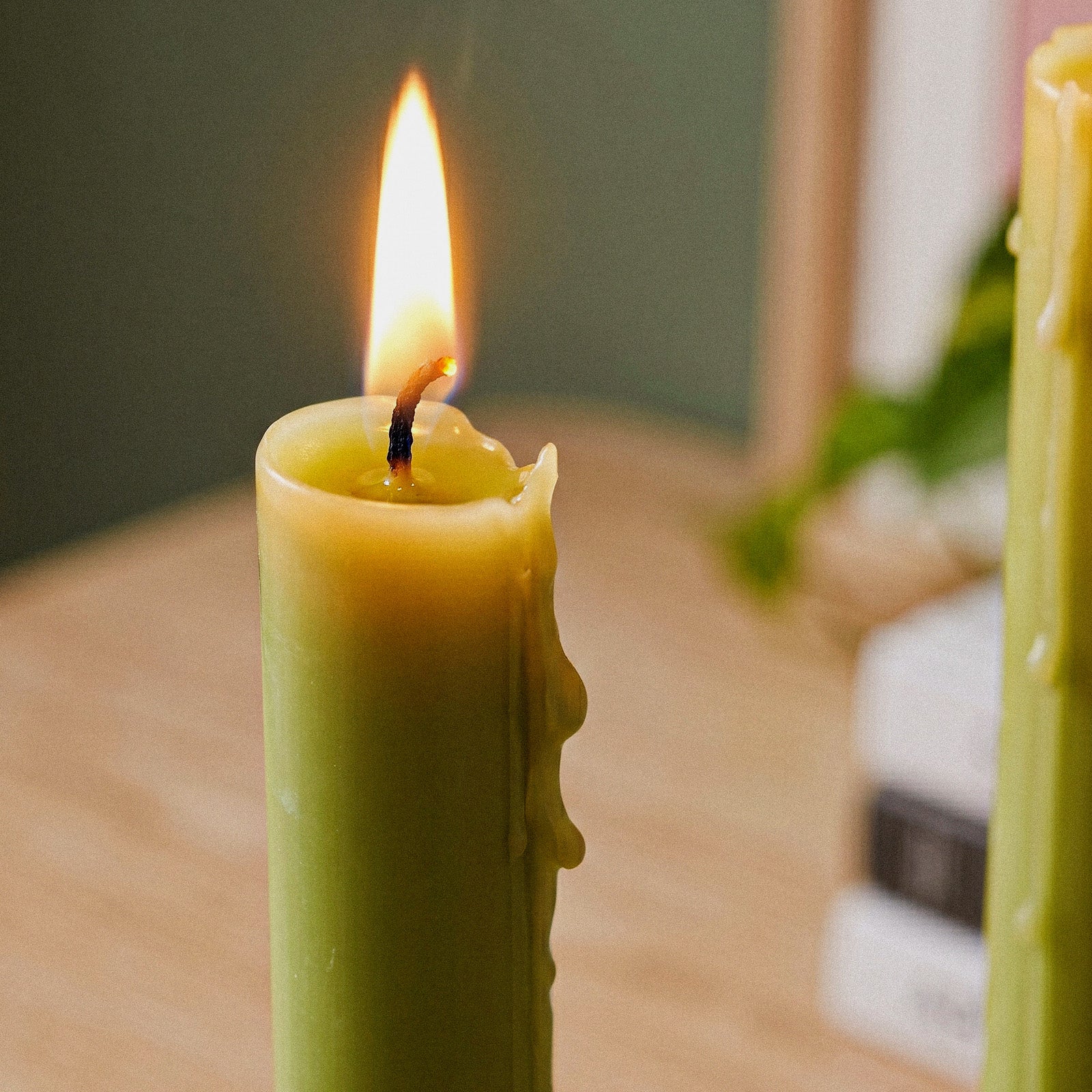 Looped Taper Acrylic Candle Mold, close-up of lit green looped taper candle with melted wax - Boowan Nicole