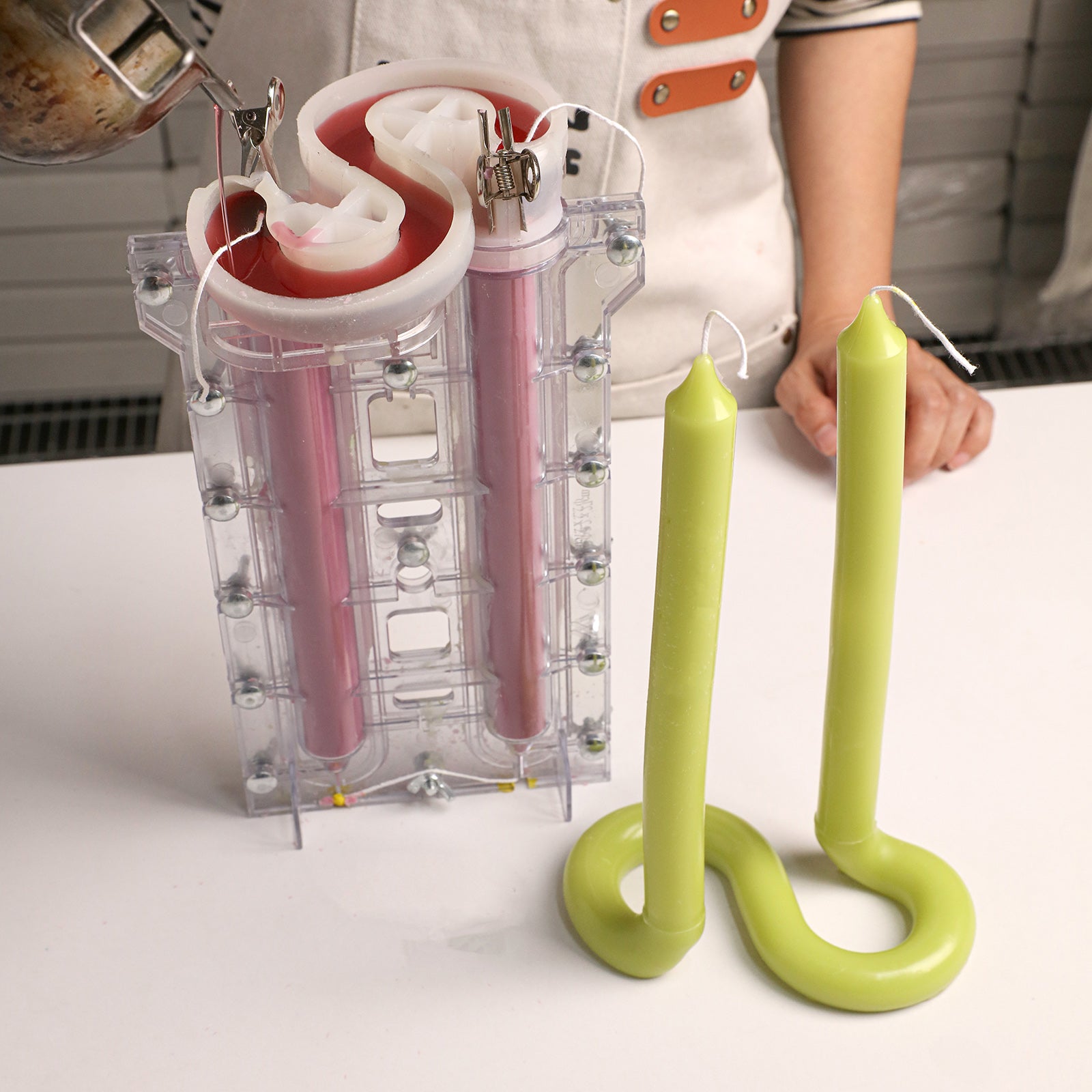 Looped Taper Acrylic Candle Mold, pouring wax into clear mold with pink wax and finished green candles - Boowan Nicole