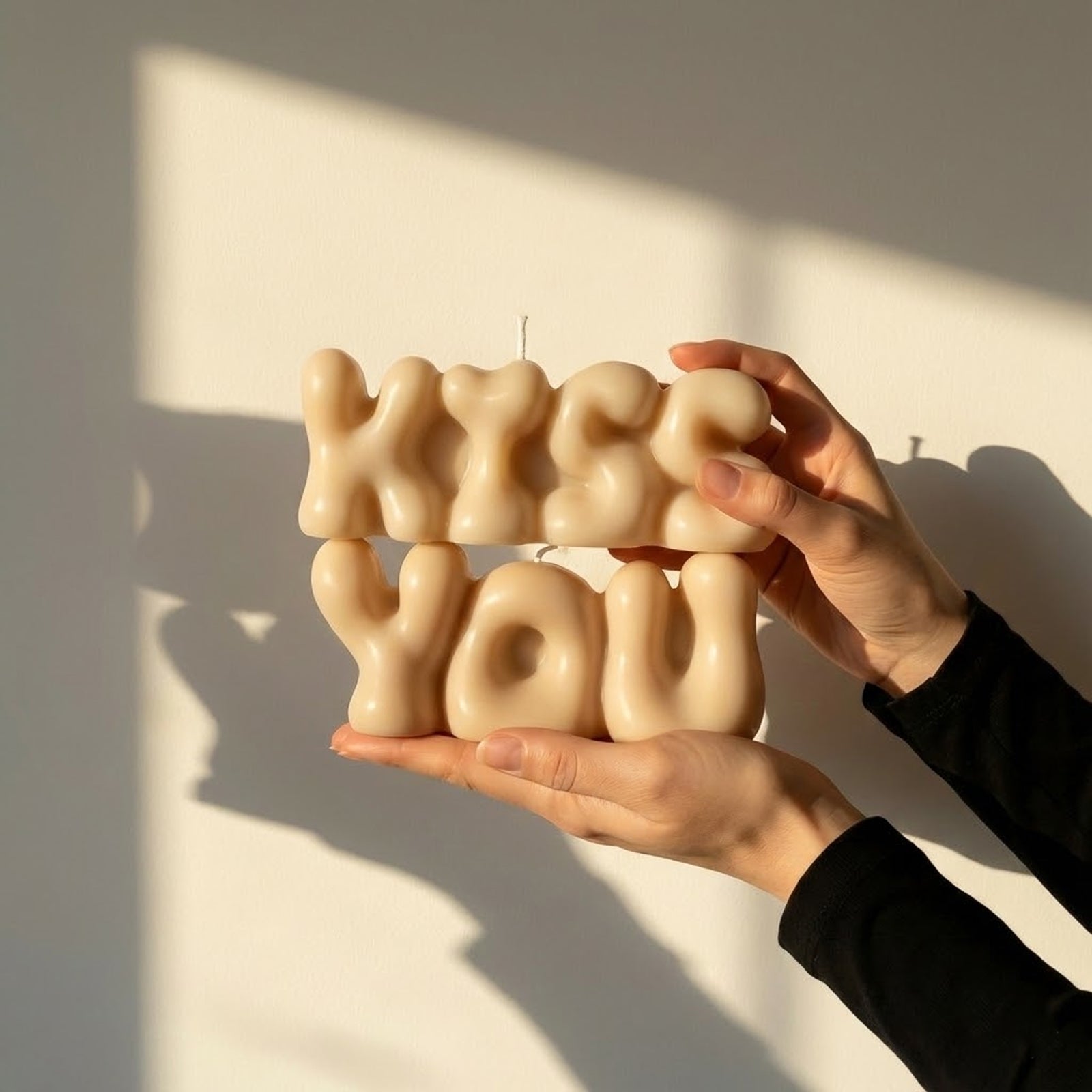 Cream "KISS YOU" puffy balloon typography candles held by hands in warm sunlight - Boowan Nicole