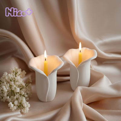 Two lit Copo de Luz calla-lily candle holders on blush satin fabric with white flowers - Boowan Nicole