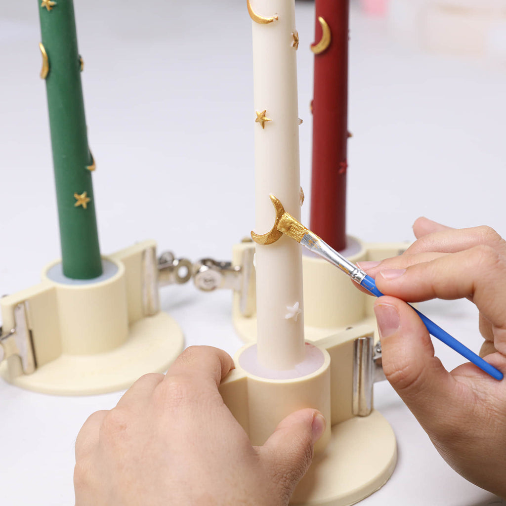 Hand-painting gold accents on the crescent-shaped holder of the ivory Midnight Magic candle - Boowan Nicole