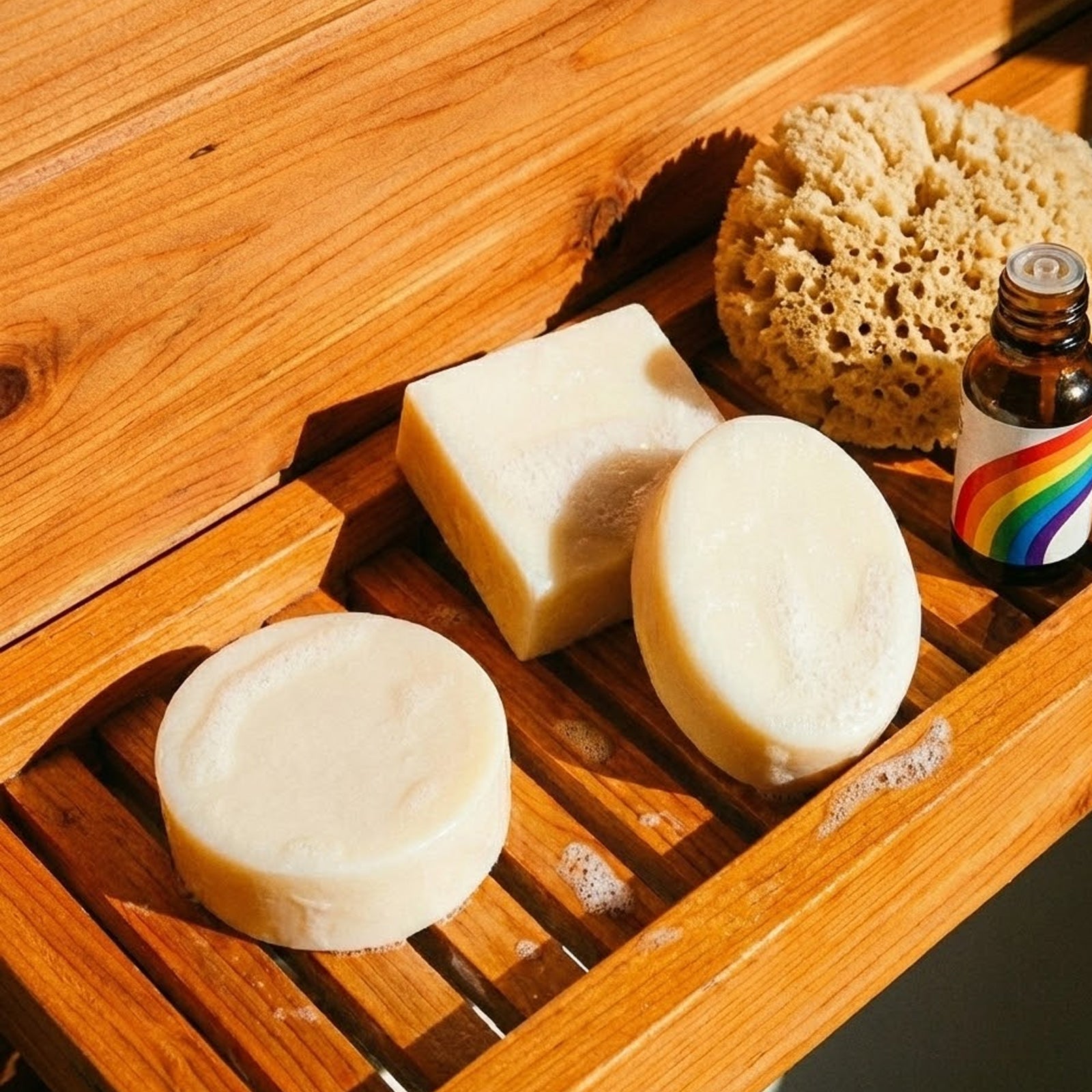 Artisanal Damask Rose Essential Oil Soap Bars on a slatted wood tray with a loofah and essential oil - Boowan Nicole