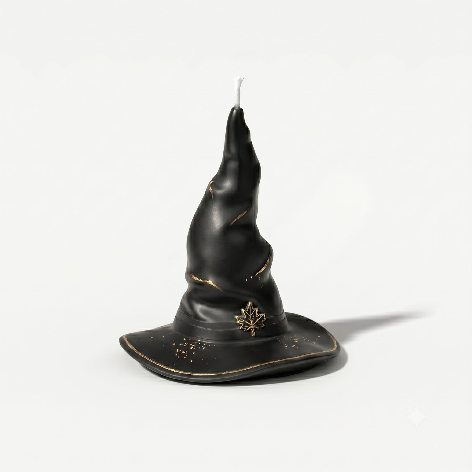 Matte black twisted wizard hat pillar candle with gold maple leaf emblem & crackle gold foil detail plain white background product shot - Boowan Nicole