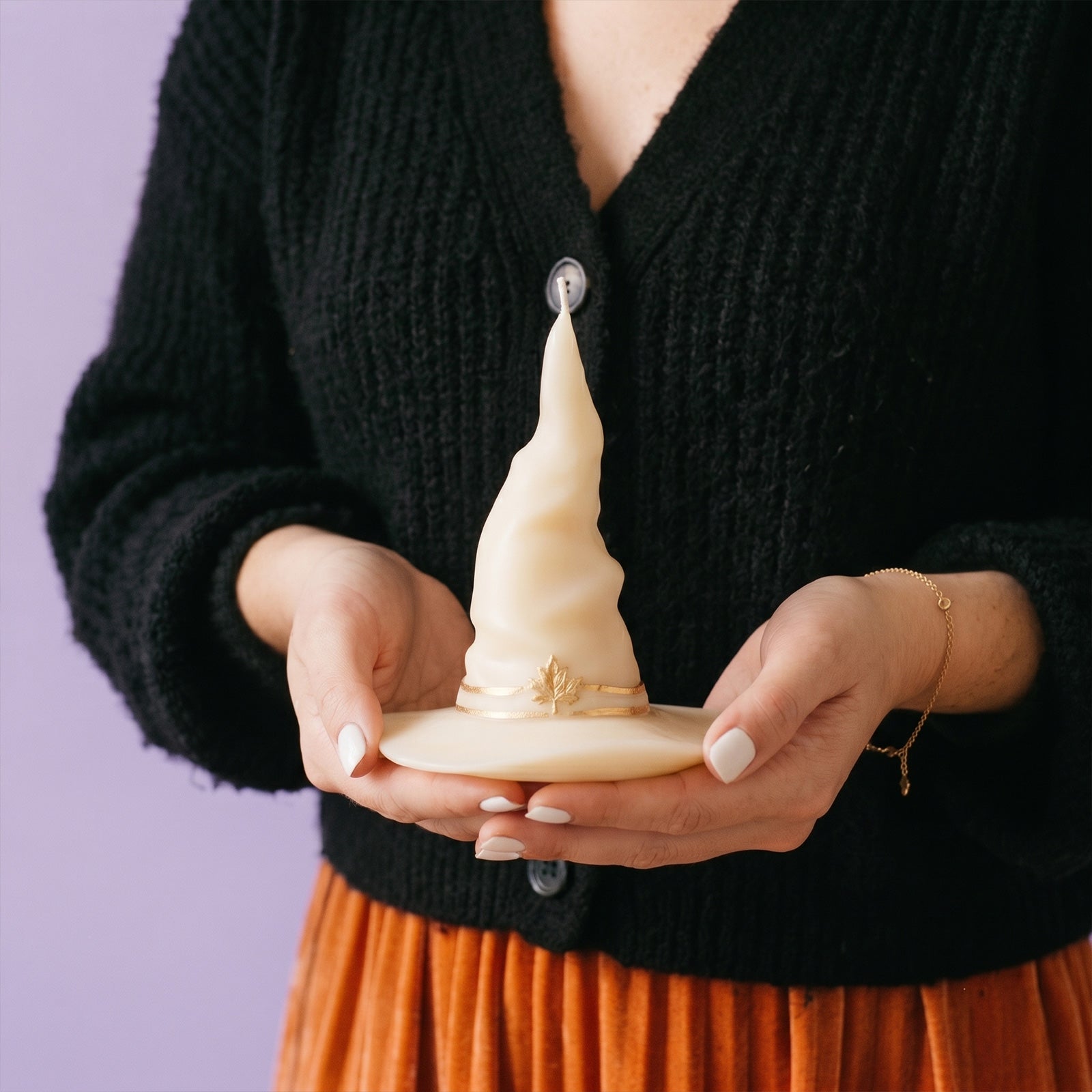  Female holding cream twisted wizard hat pillar candle with gold maple leaf detail soft indoor lifestyle shot - Boowan Nicole
