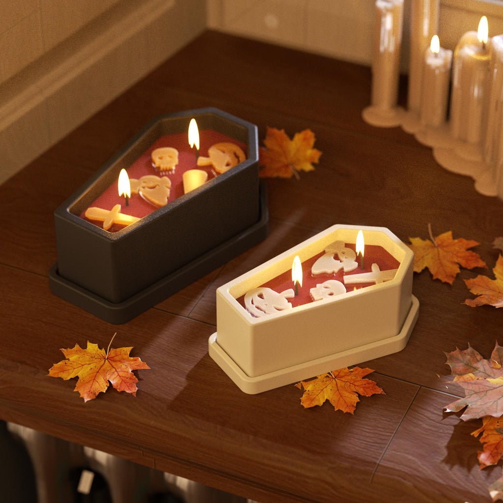 Two coffin-shaped Halloween candle jars with skull and ghost refills lit on a wooden table with autumn leaves - Boowan Nicole