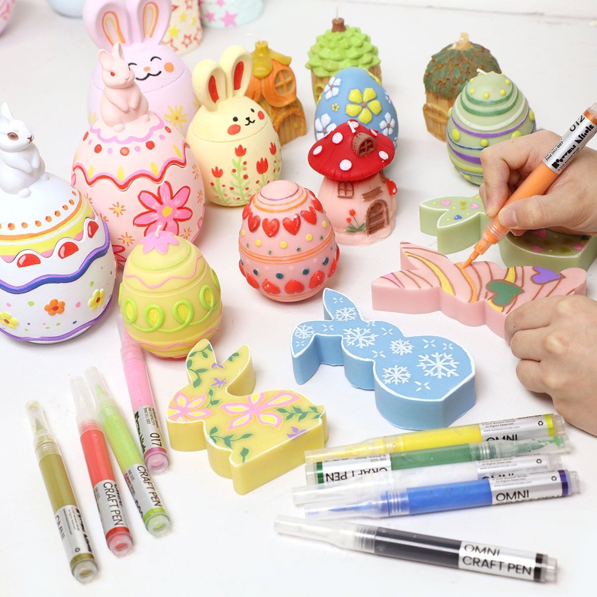 Hand painting Easter egg and bunny crafts with Omni Craft Pen refillable acrylic paint pens, showing colorful spring designs and multiple pen colors on the table - Boowan Nicole