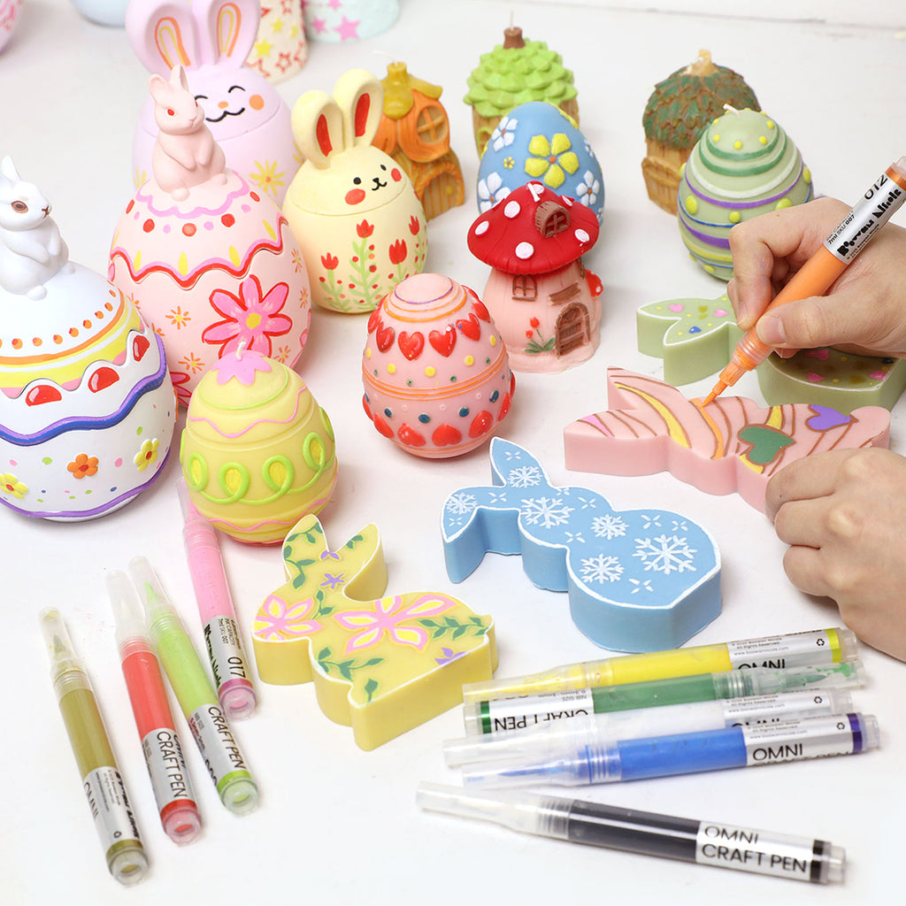 Hand painting Easter egg and bunny crafts with Omni Craft Pen refillable acrylic paint pens, showing colorful spring designs and multiple pen colors on the table - Boowan Nicole