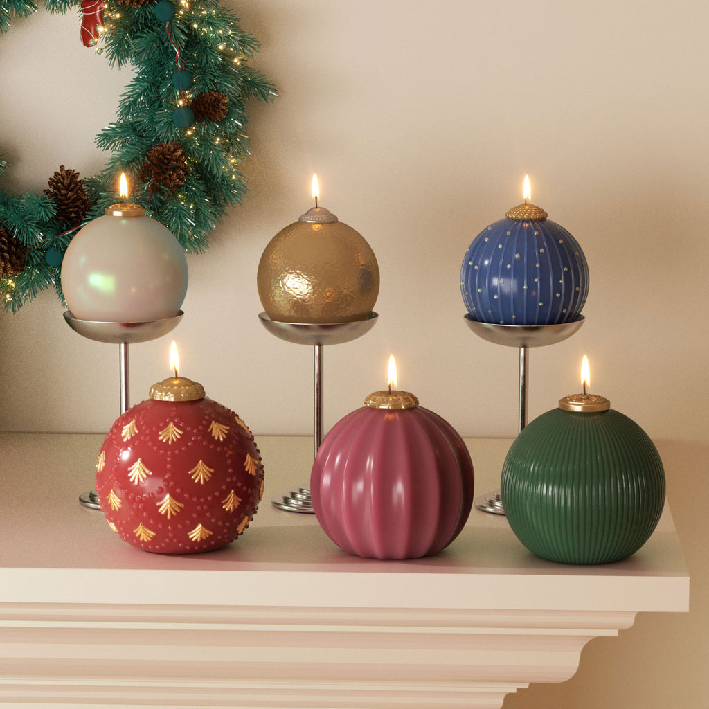 Six lit Christmas bauble candles in assorted finishes—pearlescent, hammered, pinstripe dot, fir relief, fluted, and fine rib—on a mantel with wreath - Boowan Nicole