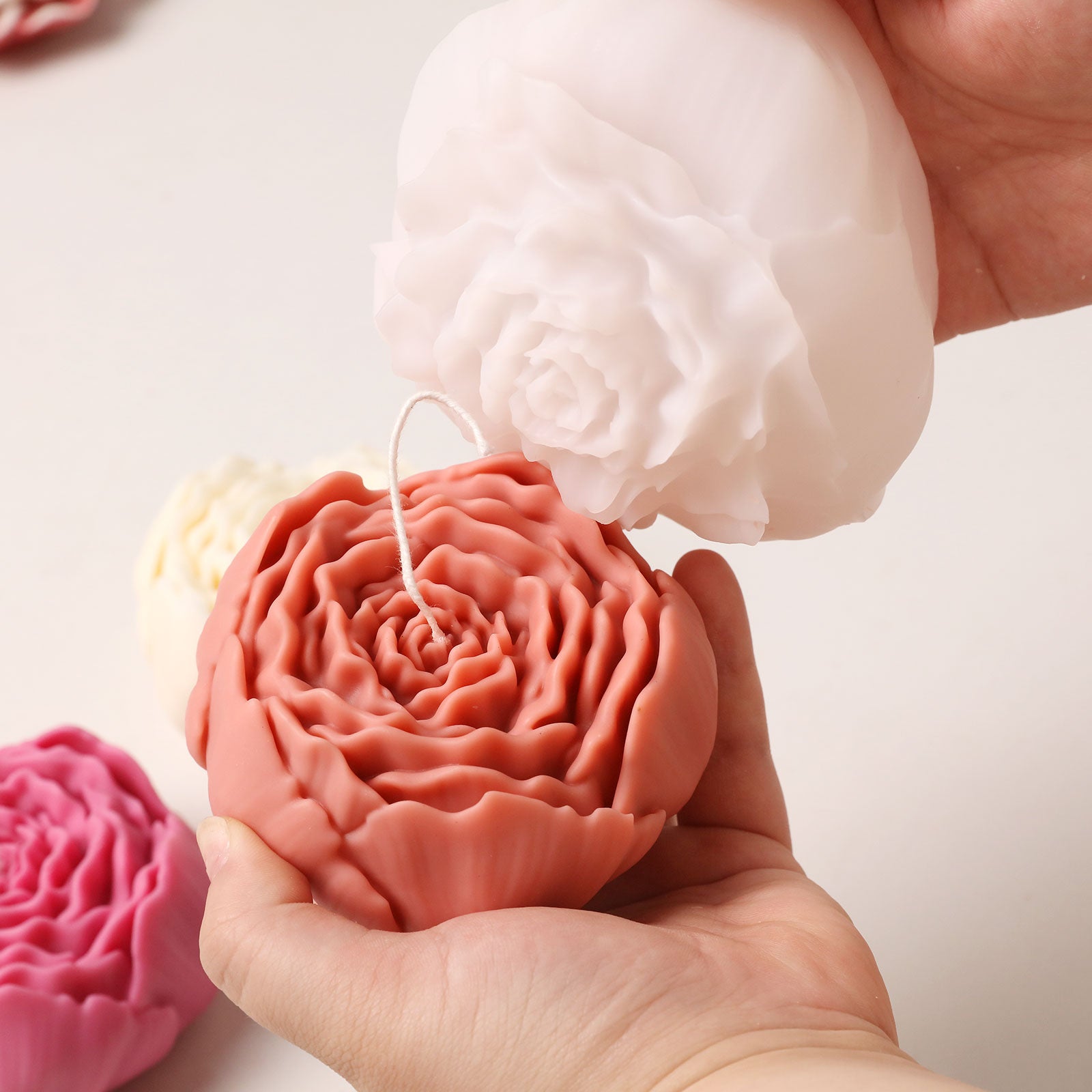 Demolding a pink peony candle from a white silicone mold, revealing the detailed layered petal structure. -Boowan Nicole