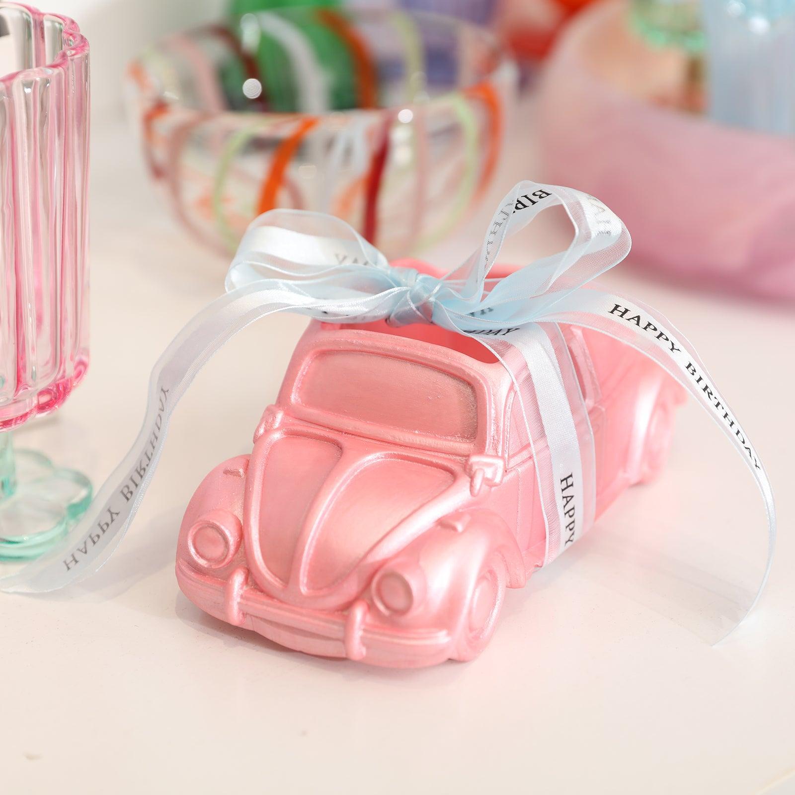 The pink car-shaped plant pot painted with mica powder is tied with a gift tie, showing that it can be used not only as a home decoration but also as a gift.